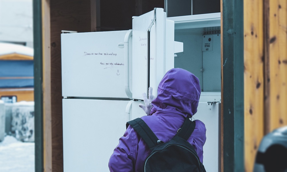Woman with backpack looking in freezer